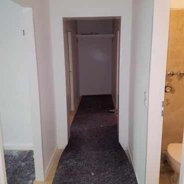 Flur während eines Komplettumbaus mit vorbereiteten Bodenflächen und frisch renovierten Wänden