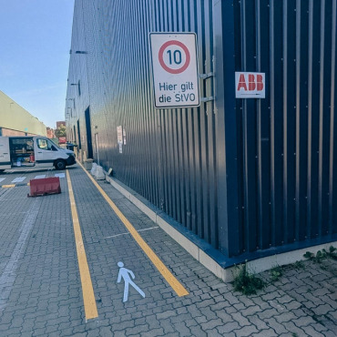 Gelbe Fahrbahnmarkierung entlang eines Logistikgebäudes