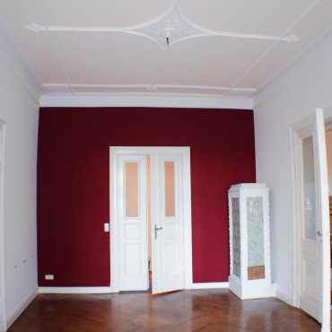 Heller Wohnbereich mit frisch gestrichenen Wänden und roter Akzentwand nach der Renovierung